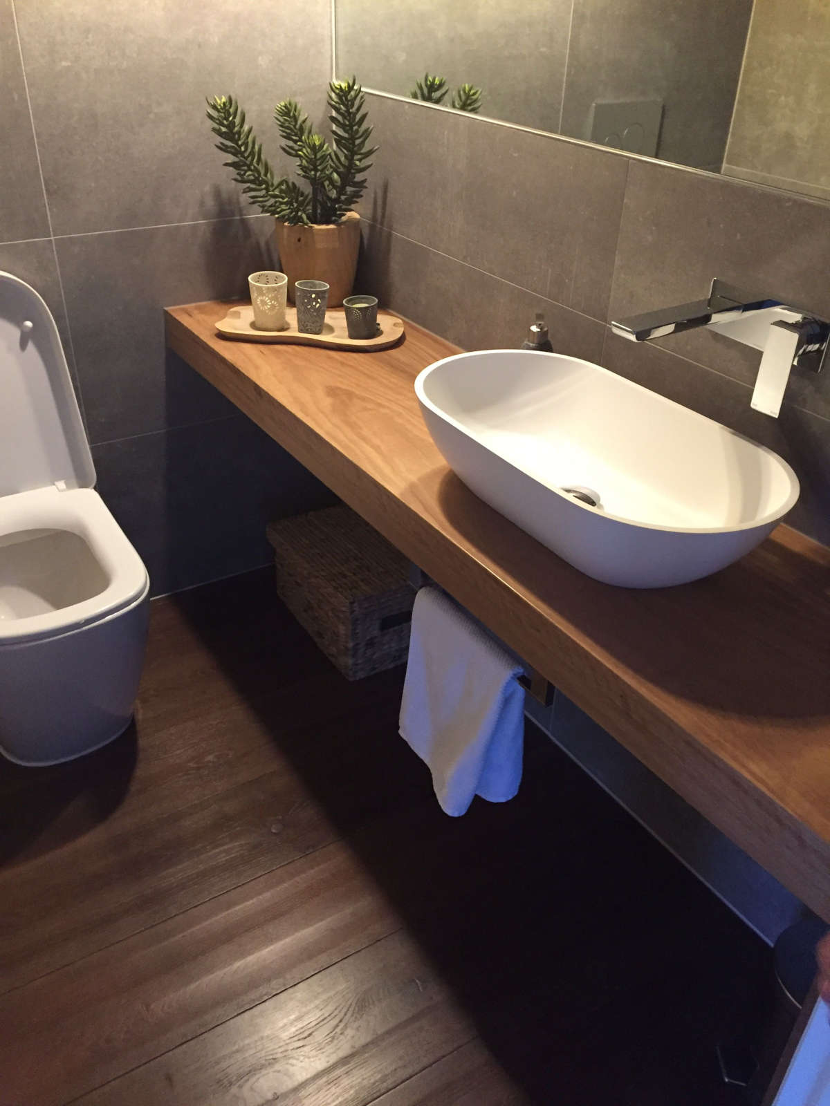 Сучасна біла овальна раковина, встановлена ​​на дерев'яній стільниці ванної кімнати