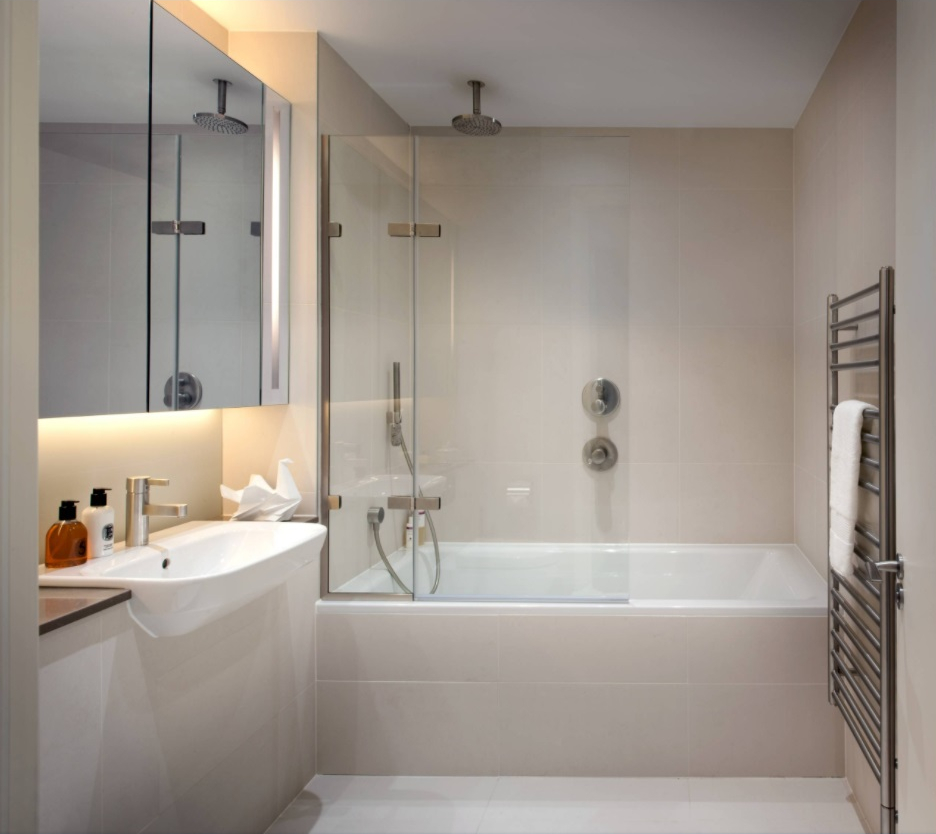 на фото зображено варіант інтер'єру ванної кімнати з повним облицюванням керамічною плиткою стін та підлоги за відсутності природного освітлення